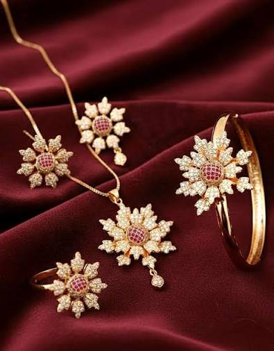 Luxury floral gold jewelry set for women featuring a necklace, earrings, ring, and bracelet with sparkling crystal accents on a burgundy velvet background.